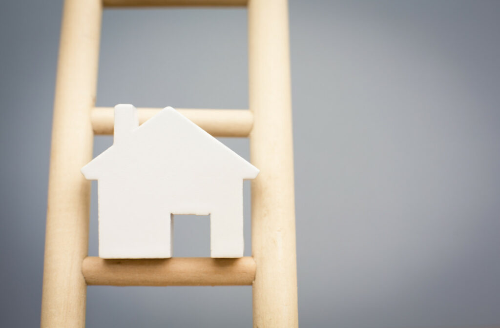 Model Houses On Rung Of Wooden Property Ladder